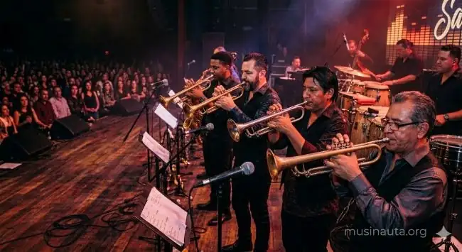 Sección de metales de una orquesta de salsa en plena actuación con trompetas y trombones brillando bajo focos