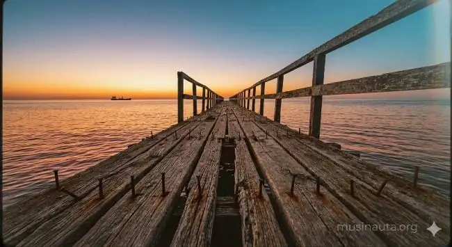 Puerto marítimo histórico al atardecer con muelle de madera y barco en el horizonte, luz naranja intensa sobre el agua