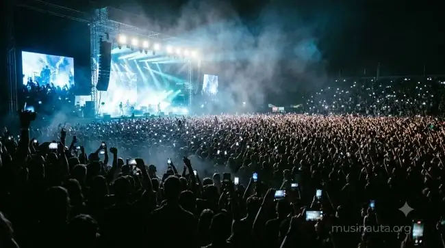 Multitud en un concierto actual de música latina con luces de teléfonos móviles encendidas